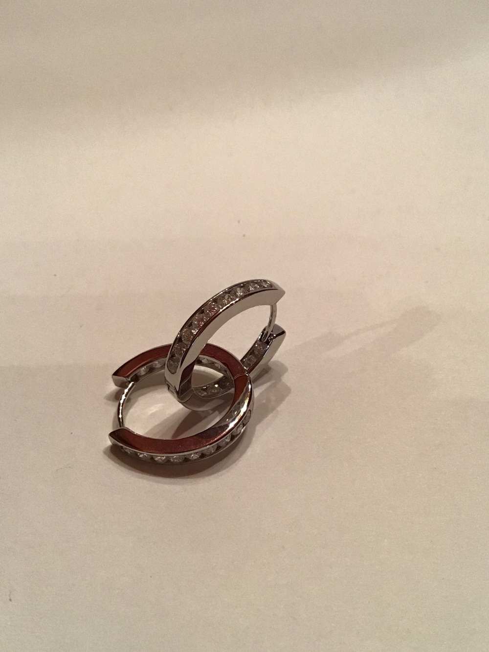 New, Rhodium plated hoop earrings, channel set CZ’s.